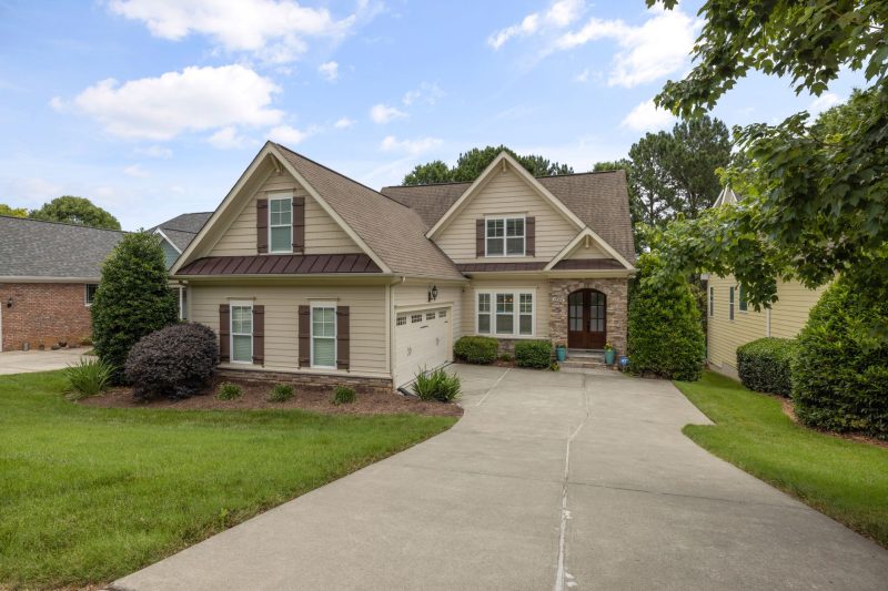 A charming suburban family home with a lush green lawn and a tidy driveway.
