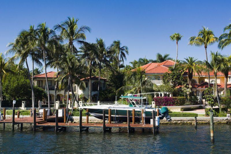 Luxury waterfront homes surrounded by palm trees, with a boat docked in Fort Lauderdale, Florida.
