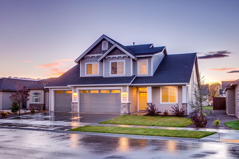 Elegant suburban home with modern architecture and a driveway, illuminated by warm sunset colors.